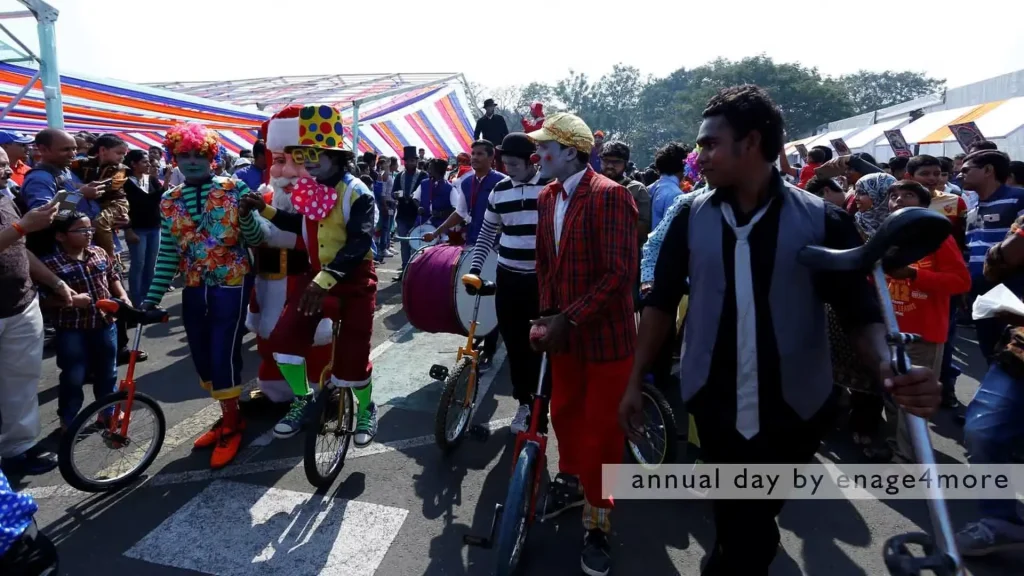 Performers dressed as clowns and Santa Claus riding unicycles and playing drums during a daytime outdoor parade.