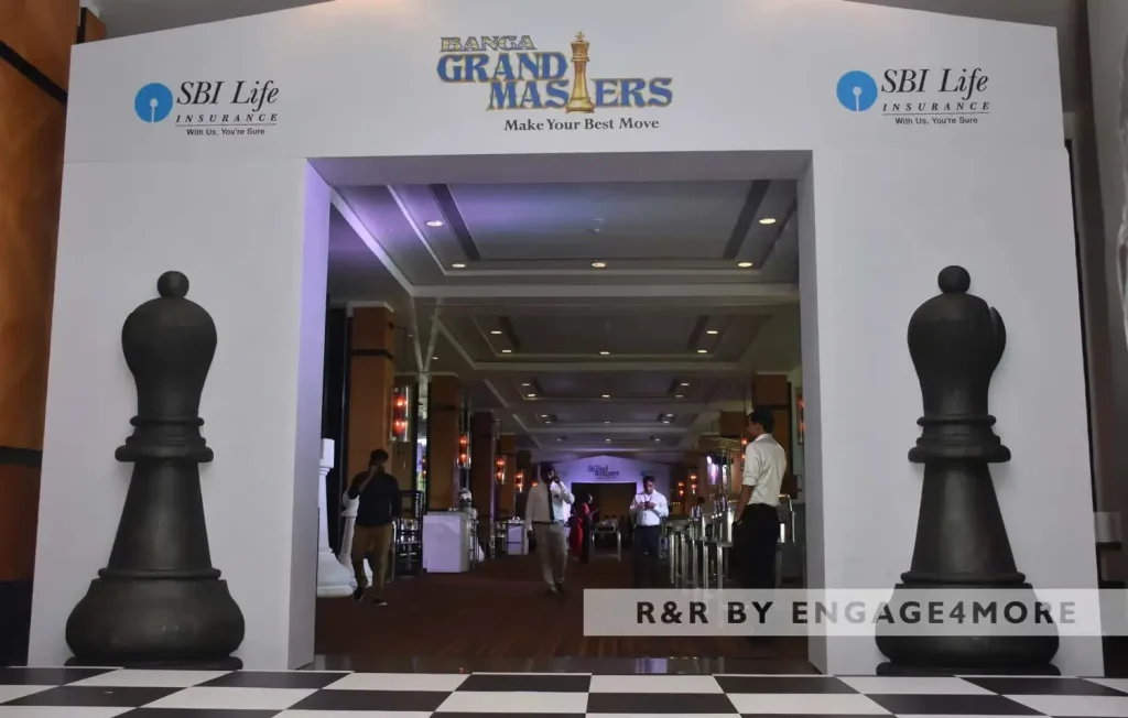 A grand entrance to a corporate event titled "Banga Grand Masters" featuring two large black chess piece pillars and a checkered floor.
