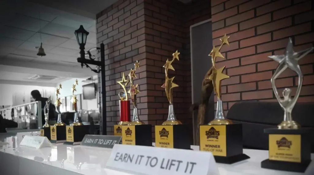 A collection of elegant corporate trophies and awards arranged on a table with professional blue and purple event lighting in the background.