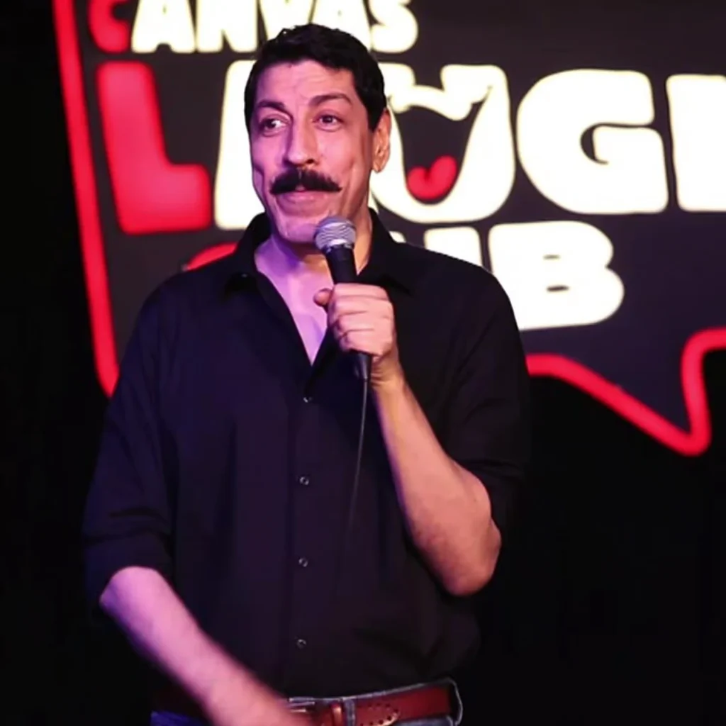 Indian stand-up comedian Rajneesh Kapoor performing on stage with a microphone