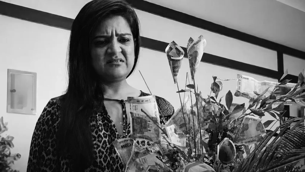 Comedian Kaneez Surka with a puzzled expression holding a bouquet of currency notes