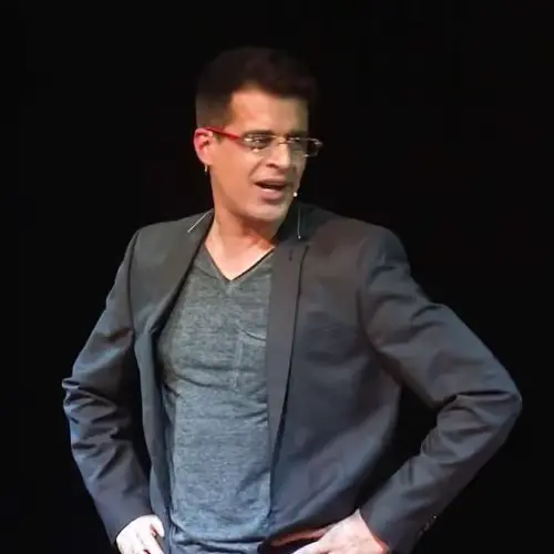 Comedian Anshu Mor performing on stage in a blazer, looking engaging and expressive against a plain black background
