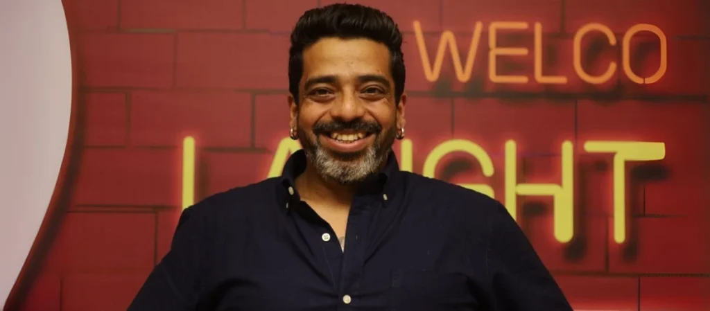 Jeeveshu Ahluwalia performing stand-up comedy on a stage with a microphone