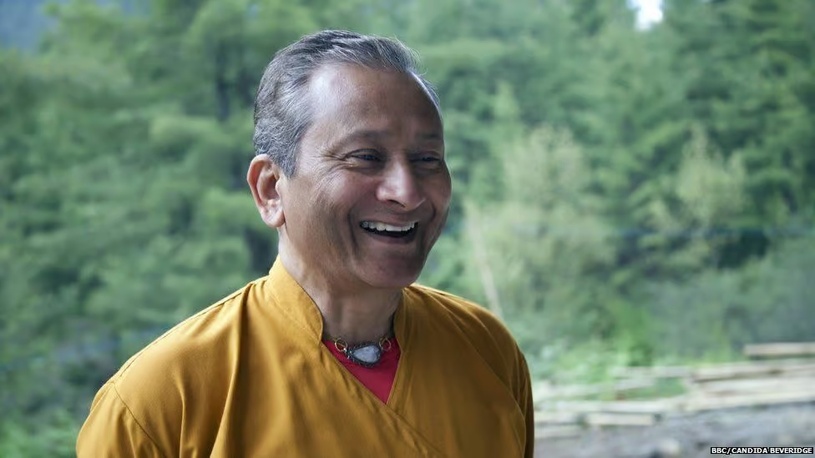 Portrait of Dr. Saamdu Chetri, Bhutanese educator and happiness researcher, smiling in a natural setting