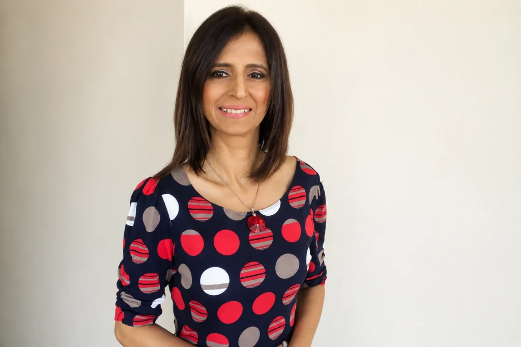 A portrait of corporate speaker Pooja Ruprell wearing a polka-dot dress
