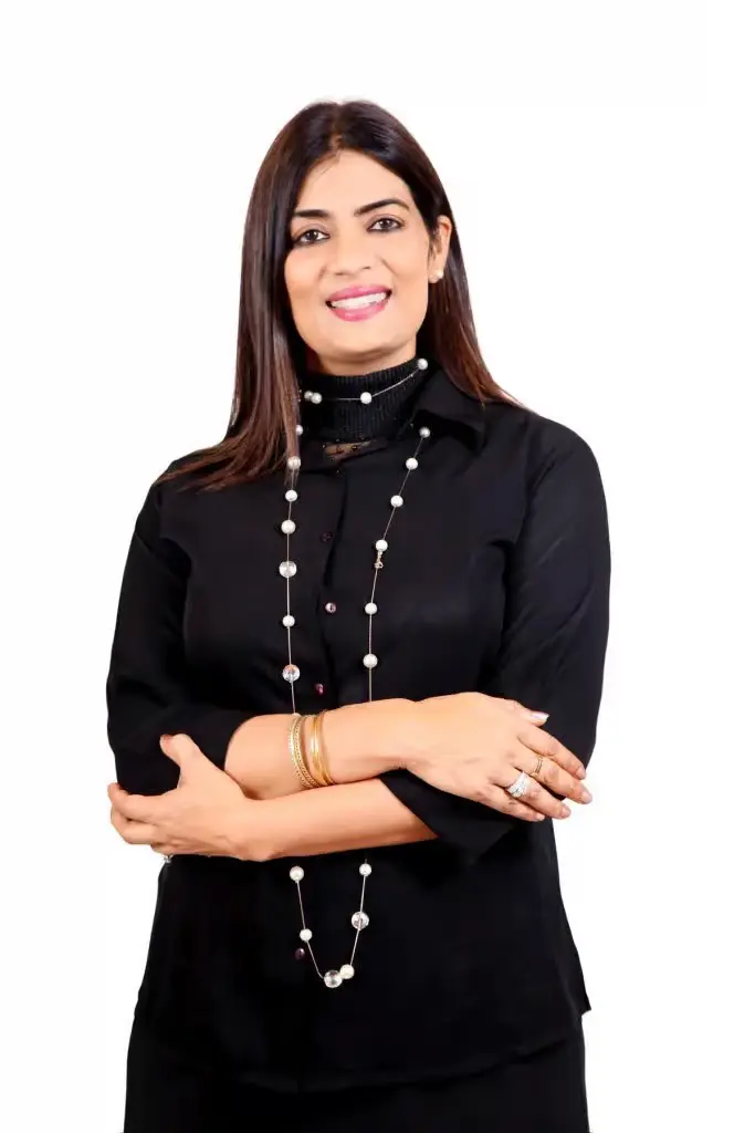 Wing Commander Namrita Chandi smiling, wearing a black shirt and long pearl necklace