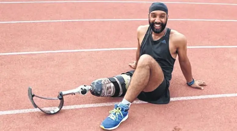 Major D.P. Singh, Kargil War veteran and athlete with a prosthetic blade, sitting on a running track and smiling