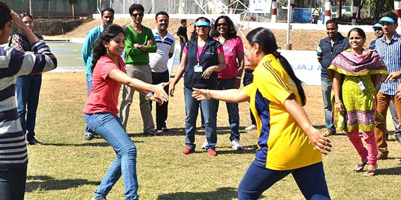 A group of corporate employees participating in an outdoor team-building activity on a grassy field, focusing on interpersonal connection and collaboration.