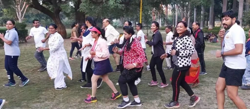 A group of corporate employees in casual and athletic wear participating in an organized outdoor group activity on a lawn, reminiscent of a school physical education drill.