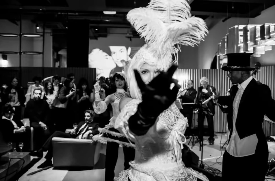A high-end corporate event space decorated in a Black and White theme, featuring a long white runway, black and white balloon arches, elegant table settings, and a large "Black & White" branded backdrop.