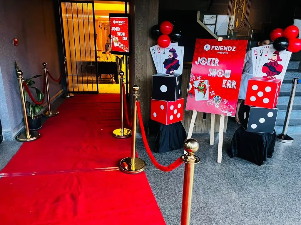 A group of corporate employees gathered around a professional green-felt casino table, interacting with a dealer and placing chips during a themed indoor event.