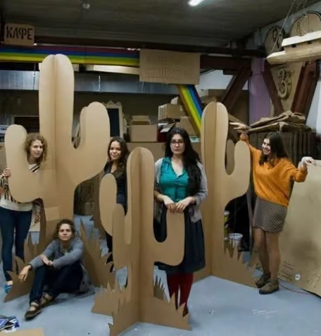 A corporate event space decorated in a Wild West theme, featuring a large "Saloon" entrance with swinging wooden doors, cactus cutouts, wooden barrels, and warm, amber ambient lighting.