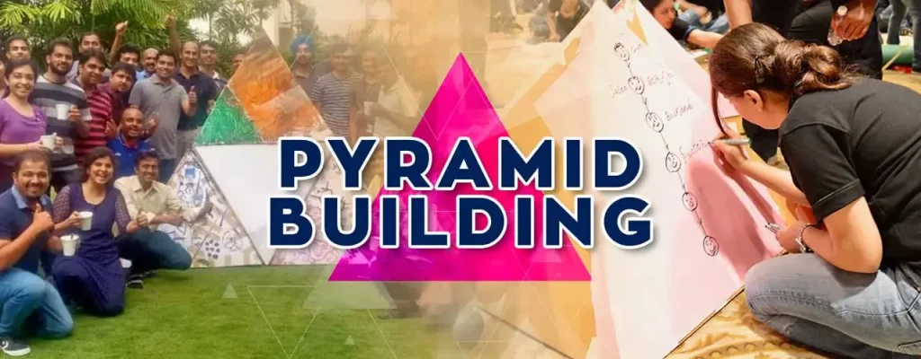 A group of employees collaborating outdoors to build and decorate a large triangular pyramid, representing the process of aligning individual efforts with a shared corporate vision.