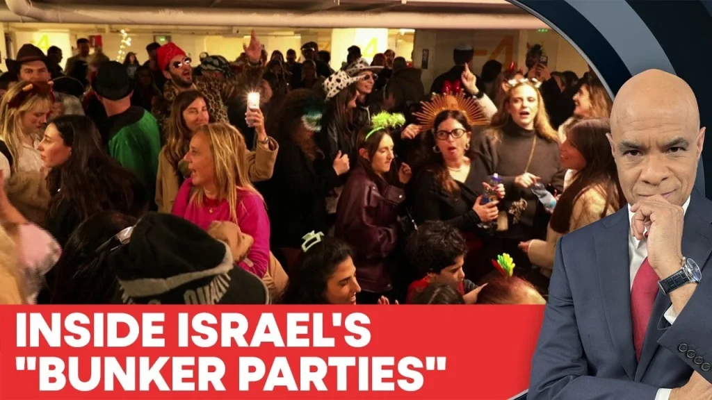 A crowded, brightly lit bunker party in Israel featuring people in costumes and casual wear gathered together during a period of conflict.