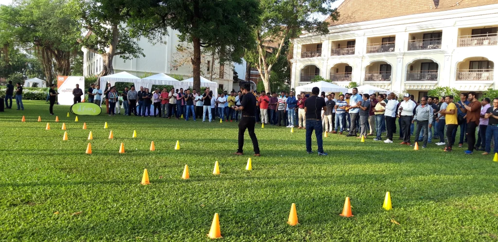 alibaug-coastal-think-tank-team-building-mumbai A high-angle view of a luxury villa in Alibaug with a red-tiled roof, surrounded by lush palm trees and tropical greenery, ideal for executive retreats.