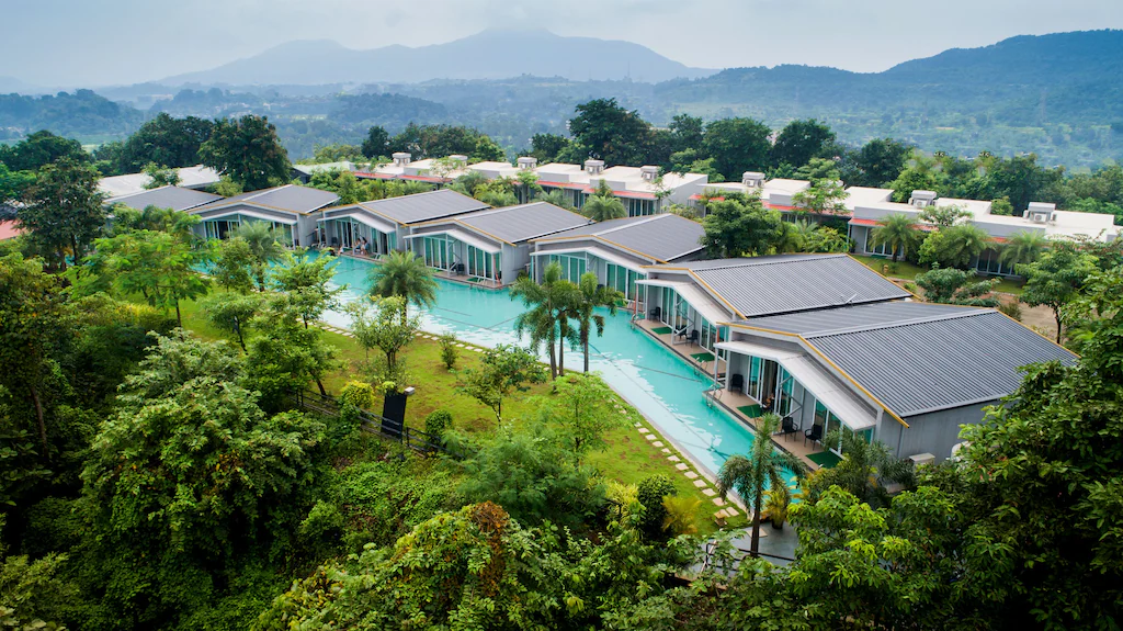 Aerial view of The Forest Club resort in Karjat featuring India's largest meandering pool and luxury villas surrounded by greenery.