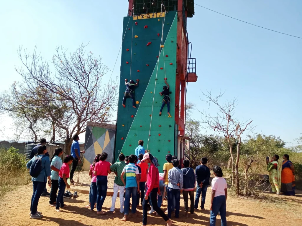 A team participating in a rock climbing wall challenge at Deccan Trails Vikarabad during an engage4more corporate offsite