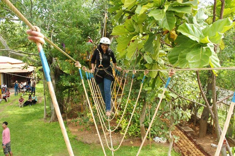 A corporate professional navigating a high-rope bridge obstacle at Discovery Village on Kanakapura Road, a premium venue for team building near Bangalore.