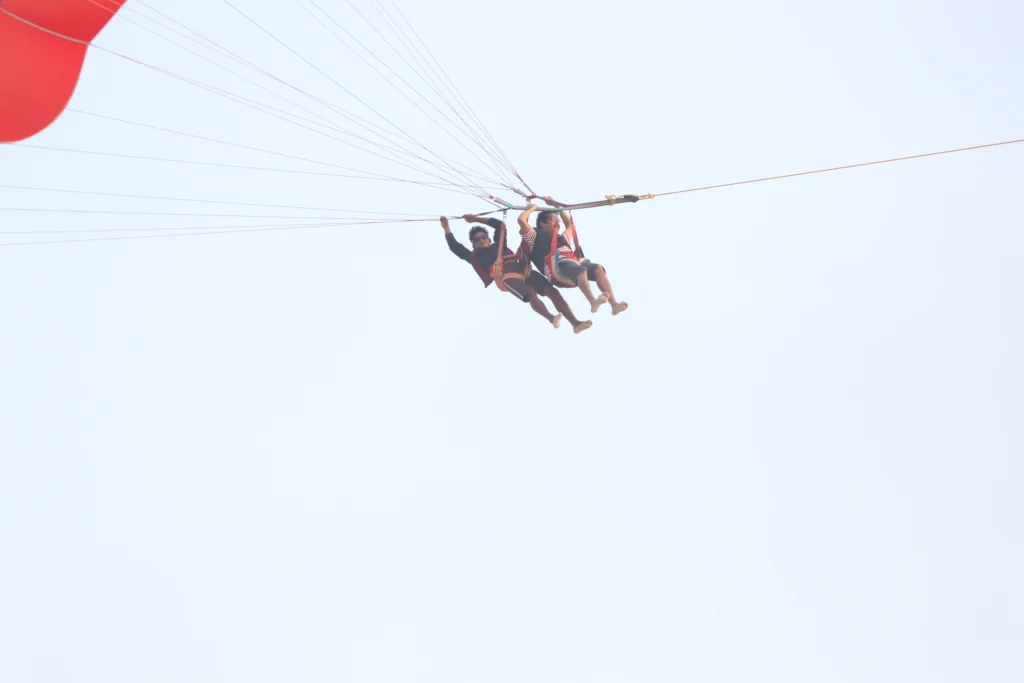 lonavala-khandala-corporate-offsite-team-building A scenic view of a mist-covered luxury resort in Lonavala, featuring a modern building with a classic tiled roof, large green lawns, and tropical trees against a clear blue sky.