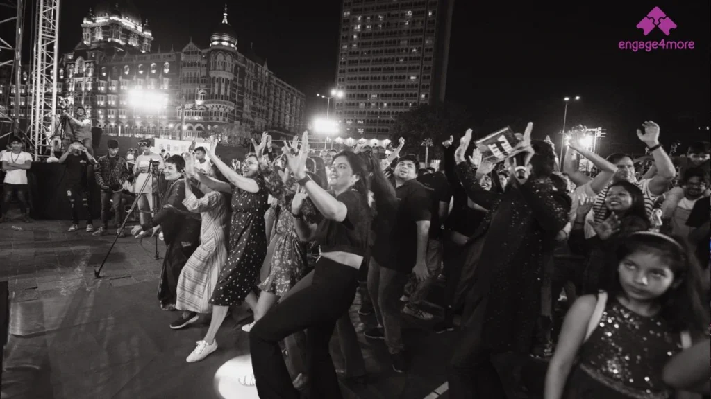 5 Best Corporate Offsite Destinations Near Mumbai for a 3-Day Strategy Retreat A high-energy black and white shot of a corporate team dancing at a night-time engage4more event with the Taj Mahal Palace and Gateway of India in the background.