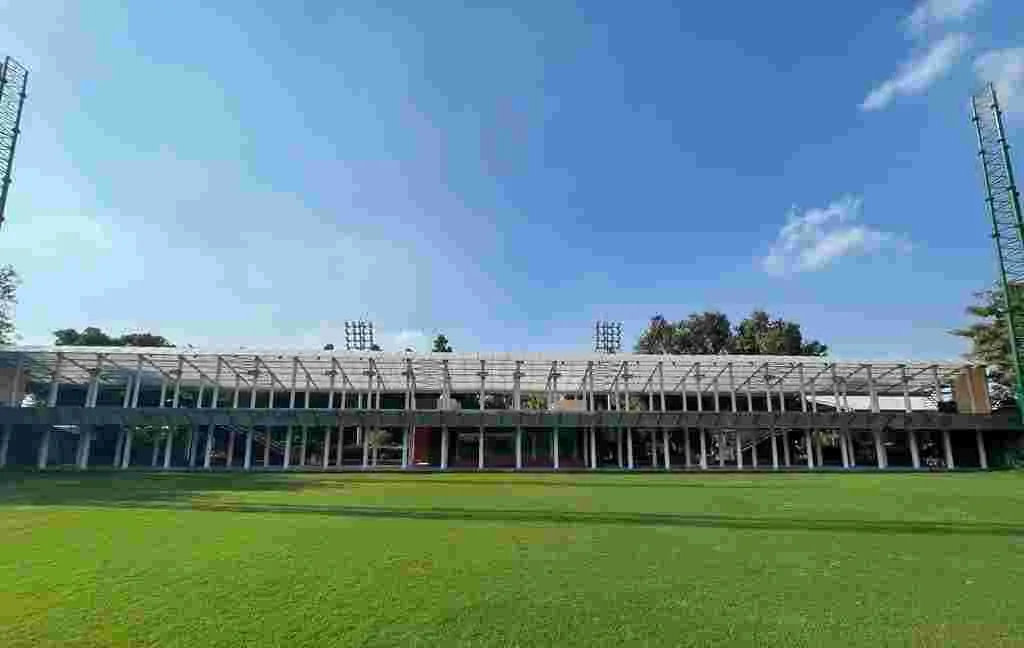 Wide landscape view of the lush green grass and floodlights at Siri Fort Golf Course in Delhi under a clear blue sky—a top urban spot for corporate sports and team engagement.