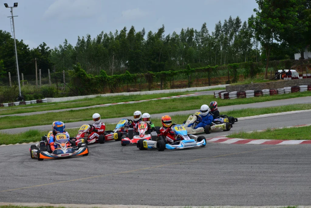 A group of corporate participants racing go-karts on the professional track at Chicane Circuit Hyderabad during a team strategy challenge