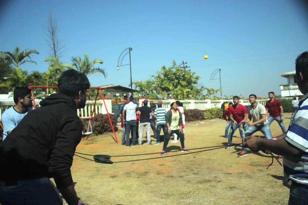 A corporate team engaged in a high-energy Super Slingshot activity on a sunny resort lawn in Jaipur.