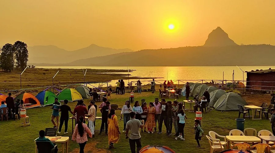 Corporate teams enjoying a lakeside camping retreat at Pawna Lake with tents and sunset views, focusing on culture building and kinship