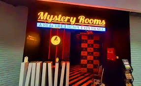 mystery-rooms-mumbai-escape-room-team-building The neon-lit entrance of Mystery Rooms in Mumbai, featuring a "Real Life Escape Experience" sign with red and black thematic decor.