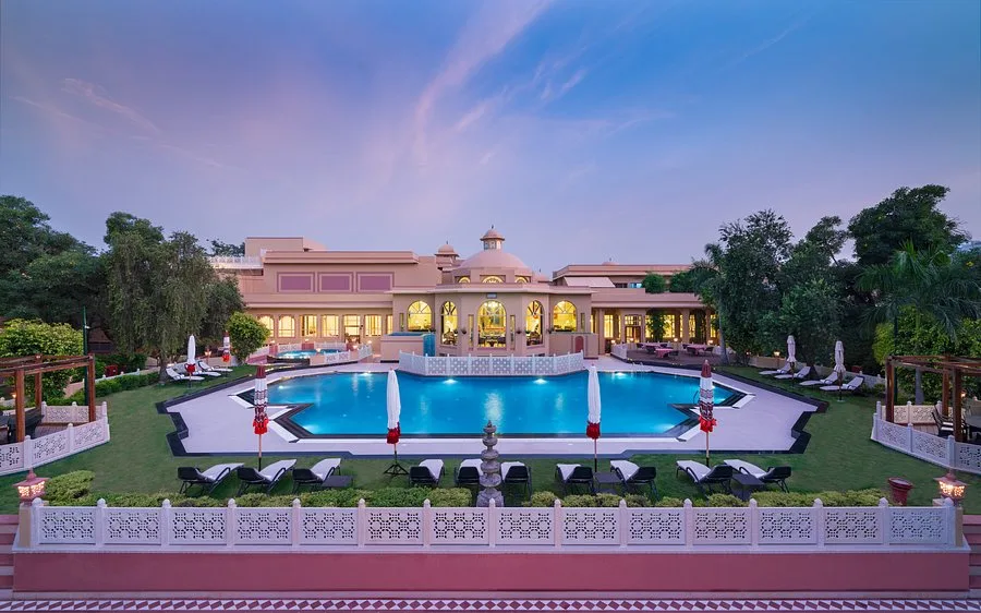 Wide shot of the expansive swimming pool and Rajasthani haveli-style architecture at Heritage Village Resort & Spa, Manesar—a luxury venue for corporate retreats and large-scale team outings near Gurgaon.
