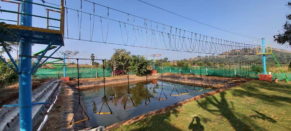 A professional high-rope obstacle course over a pool at Wild Valley Adventure Retreat, a lush team-building venue on Kanakapura Road, Bengaluru