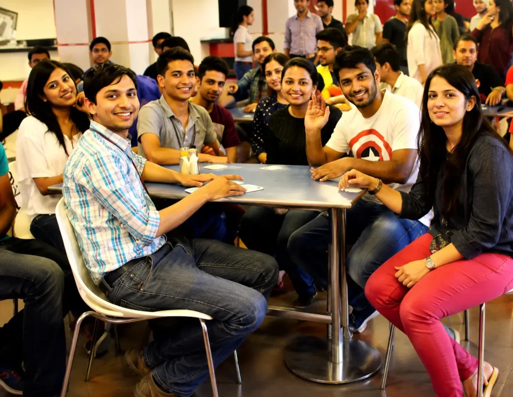 A group of smiling employees sitting around a table, participating in a Musical Tambola session in an office setting