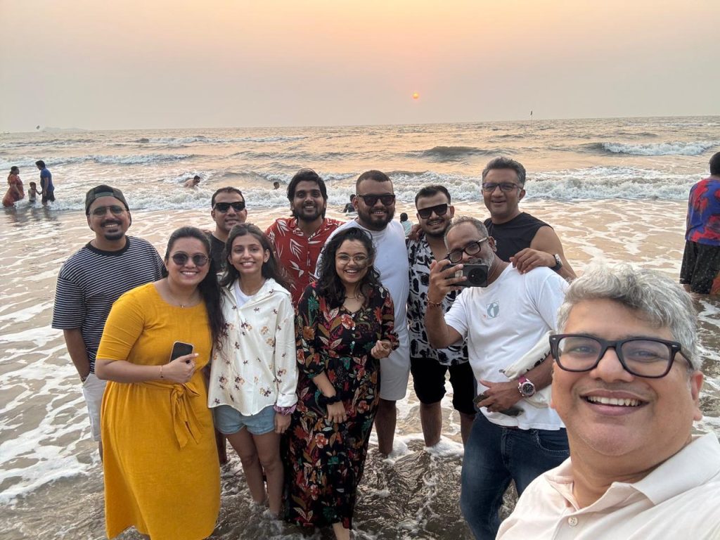 A group of professionals smiling and bonding together on the beach during an engage4more company offsite
